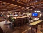 Vista interior del bar con barra larga y mesa de shuffleboard