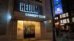 Fachada exterior nocturna del Helium Comedy Club con letrero iluminado