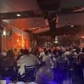 Interior del club con público sentado y ambiente de show en vivo