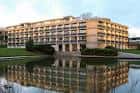 Fachada del edificio principal reflejada en el agua, mostrando su diseño arquitectónico