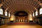 Interior del Gran Salón vacío, destacando su techo abovedado ornamentado y butacas rojas frente al escenario
