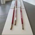 Instalación artística con varas rojas y blancas sobre una superficie blanca
