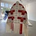 Gran pieza textil colgante con patrones rojos y blancos en el espacio expositivo
