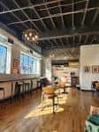 Interior del Yellowbird Coffee Bar con techo industrial y mesas de madera