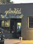 Vista frontal del Yellowbird Coffee Bar con letrero iluminado en la pared