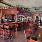 Interior del bar con barra de madera y taburetes altos