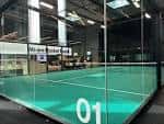 Pista de pádel número 01 en Rocket Padel Ilford, mostrando el suelo verde y las paredes transparentes