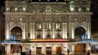 Fachada nocturna del teatro iluminada con detalles arquitectónicos visibles