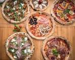 Vista cenital de varias pizzas artesanales dispuestas sobre una mesa de madera
