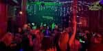 Escenario iluminado en verde dentro del club con público animado