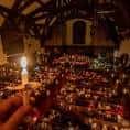 Vista panorámica del interior de la iglesia iluminado por velas durante una ceremonia nocturna