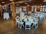 Sala de eventos preparada para una celebración con mesas redondas y sillas blancas