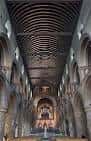Interior de la nave central con bóveda de madera y arcos románicos hacia el altar