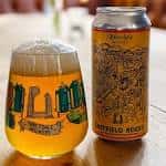 Copa de cerveza y lata sobre una mesa de madera