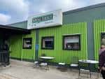 Fachada exterior del Spring Street Tavern con paredes verdes y mesas al aire libre
