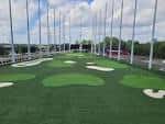 Campo de práctica de golf con múltiples tejas y césped artificial bajo techo