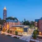 Escena nocturna del campus con edificios iluminados y la torre característica al fondo