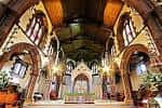 Interior de la iglesia con bóveda decorada, vitrales y altar central iluminado