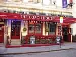Fachada exterior de The Coach House en Londres con toldo rojo y letrero visible