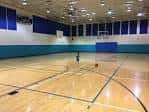 Interior de la cancha deportiva con piso de madera y canastas