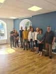 Interior de una sala de eventos con suelo de madera y grupo de personas reunidas