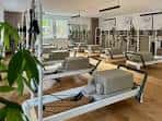 Interior del estudio Luma Pilates con máquinas reformadoras y plantas decorativas