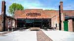 Vista exterior del Beer Hall de Columbus Brewing Company con fachada de ladrillo y patio