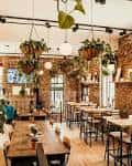 Interior del establecimiento con decoración industrial, mesas altas y plantas colgantes