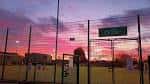 Atardecer sobre el recinto deportivo con vallas iluminadas por la luz crepuscular