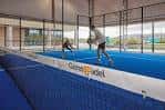 Interior de una pista cubierta con jugadores en acción y suelo azul
