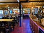 Interior del bar con barra larga y mesas de madera