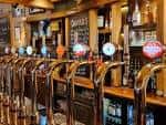 Detalle de la barra con grifos de cerveza y botellas en estantería