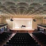 Interior del auditorio con escenario, piano y butacas dispuestas para recitales musicales