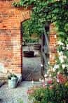 Arco de ladrillo con vegetación y camino en el jardín