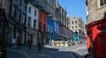 Vista panorámica de Grassmarket con edificios históricos y coloridos bajo un cielo despejado
