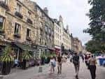 Calle peatonal de Grassmarket con gente caminando y terrazas al aire libre