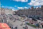 Plaza amplia de Grassmarket con multitud de visitantes y puestos durante el día