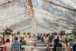 Interior de carpa para evento con mesas decoradas y iluminación cálida