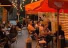 Terraza exterior con toldos naranjas y clientes sentados
