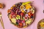 Detalle de una tabla de aperitivos con uvas, higos y queso en un plato redondo