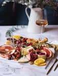 Plato de aperitivos servido con copa de vino blanco y jarrón decorativo