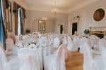 Sala de eventos decorada para boda con sillas cubiertas y mesa central