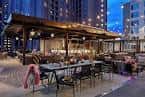Área de comedor al aire libre con iluminación cálida y ambiente urbano