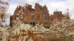Fachada de Aston Hall rodeada de árboles en flor durante la primavera