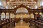 Vista del interior de la nave principal de la iglesia con bancos de madera y detalles arquitectónicos