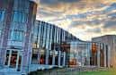 Fachada curva de Hillman Hall al atardecer con cielo nublado