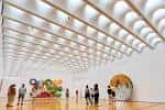 Interior del museo con techo de cúpulas y visitantes observando arte
