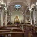 Interior de la basílica mostrando el altar principal, bóvedas y bancos de madera