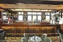 Interior del bar principal con mostrador de madera y estanterías de bebidas