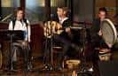 Actuación musical en vivo con tres artistas en un escenario